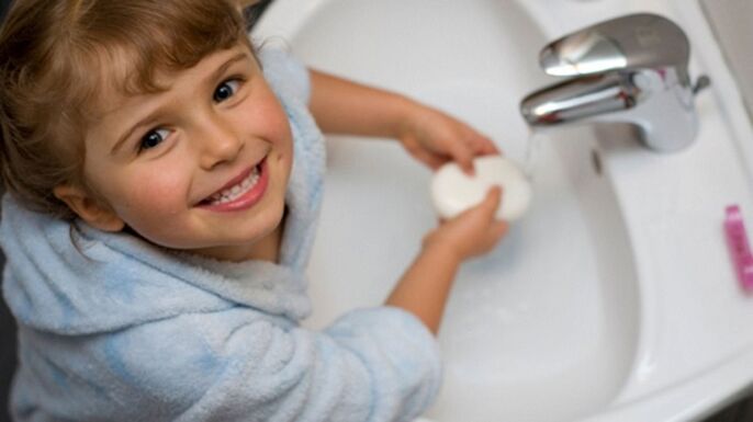 das Kind wäscht seine Hände mit Seife, um Würmer zu verhindern